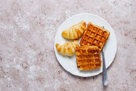 Delicious breakfast with coffee, orange juice, waffles,croissants,jam,nut paste on light...