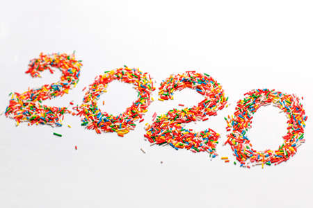 Creative Happy New 2020 Year. Colorful number shape with bright rainbow sugar sprinkles isolated on whiteの写真素材