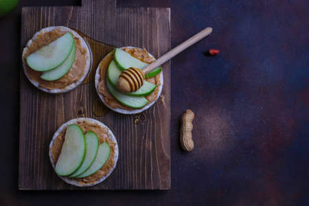 Crunchy natural peanut butter sandwich with rice cake bread and green apple slices and honey. Proper nutrition diet vegetarian breakfastの写真素材