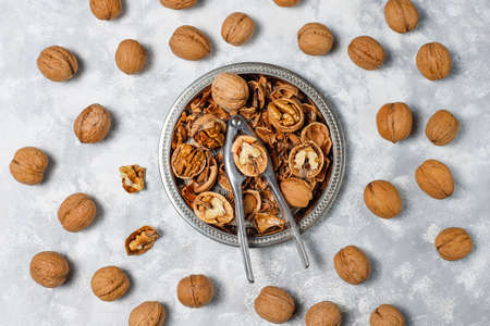 Whole walnuts in shell in food metal basket, walnut kernels. Top view on concrete backgroundの写真素材