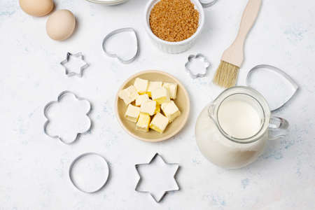 Ingredients for baking - milk,butter,eggs, flour wheat,brown sugar,cookie cutters white background,top viewの写真素材