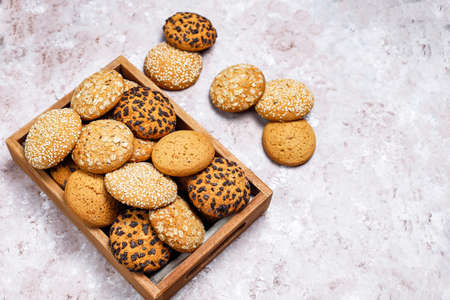Set of various american style cookies in wooden tray on light concrete background. Shortbread with sesame seed, peanut butter, oatmeal and chocolate chip cookies.の写真素材