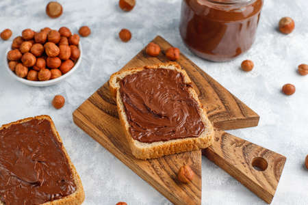 Chocolate spread or nougat cream with hazelnuts in glass jar on concrete background, copy spaceの写真素材