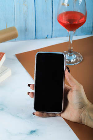 Taking a black smartphone in the hand around a glass of wine