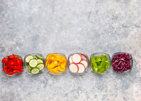 Cutting board with slices of colorful bell peppers on light background. Sliced sweet peppers in...