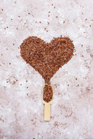 Heart shaped flax seeds on concrete background with space for copy,top viewの写真素材