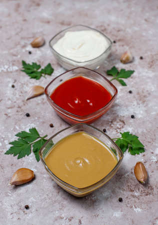 Homemade ketchup,mustard and mayonnaise sauce and ingredients on brown concrete background. Top view