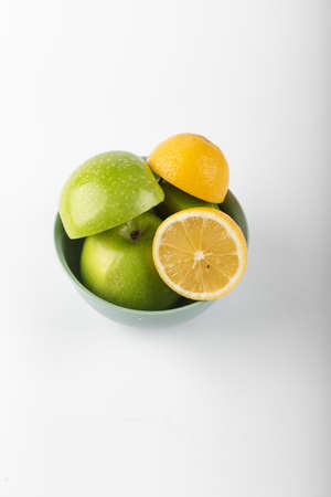Green apple and lemons in a silver bowlの写真素材