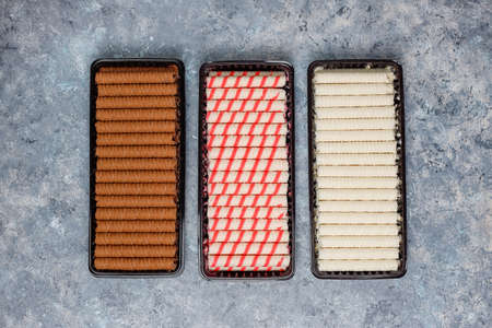 Plate with tasty wafer roll sticks on concrete background, top view. Crispy foodの写真素材