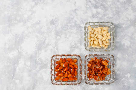 Peeled (blanched) and unblanched whole almonds in glass bowls on grey concrete backgroundの写真素材