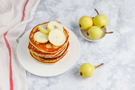 Homemade breakfast: american style pancakes served with pears and honey with a cup of tea on concrete background. Top view and copy spaceの写真素材