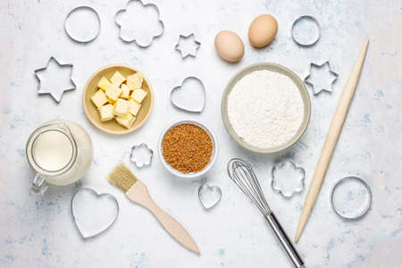 Ingredients for baking - milk,butter,eggs, flour wheat,brown sugar,cookie cutters white background,top viewの写真素材