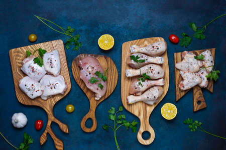 Raw chicken meat fillet, thigh, wings and legs with herbs ,spices,lemon and garlic on dark blue background. Top viewの写真素材