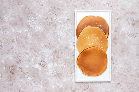 homemade fried pancakes on white plate on a brown concrete background