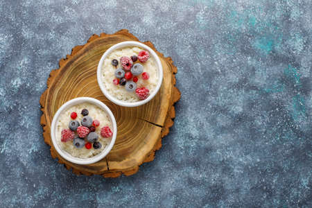 Rice pudding with frozen blueberries and raspberries in white bowlの写真素材