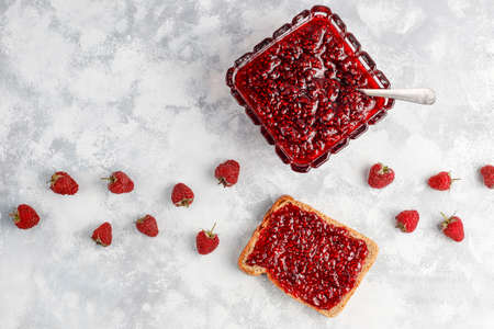 homemade raspberry jam with fresh raspberries on concrete background,top view