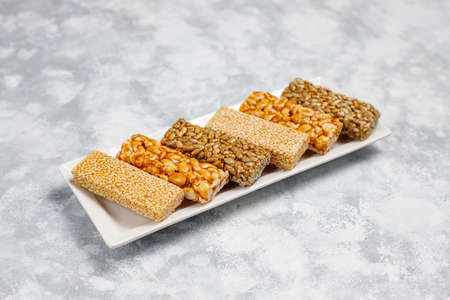 Granola bar. Healthy sweet dessert snack. Sesame, peanut, sunflower in honey. Gozinaki is Georgian national food, oriental sweet. Top view on concrete backgroundの写真素材