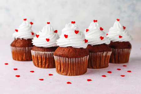 Valentines day background, chocolate cupcakes with heart shaped candies,top view