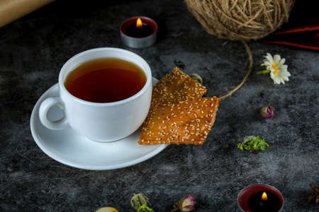 A cup of tea with crackers on black marbleの写真素材