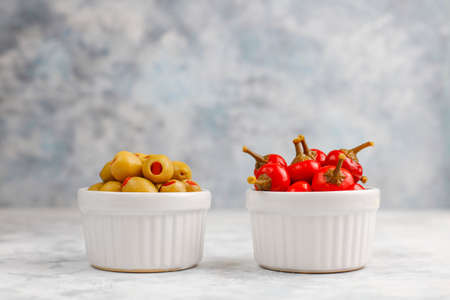 Pickled small round red hot cherry chili peppers on grey concrete backgroundの写真素材