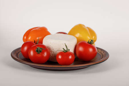 Cheese, tomato and peppers in a brown plateの写真素材