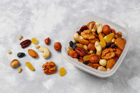 Assortment of nuts in plastic container. Cashew, hazelnuts, walnuts, pistachio, pecans, pine nuts,...