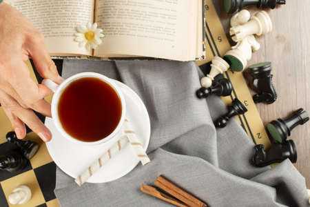 A cup of tea, a book and chess figuresの写真素材