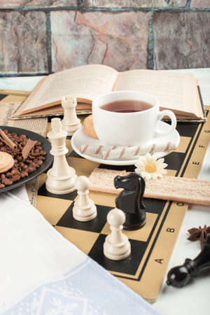 A cup of tea and some chess figures on a chessboardの写真素材