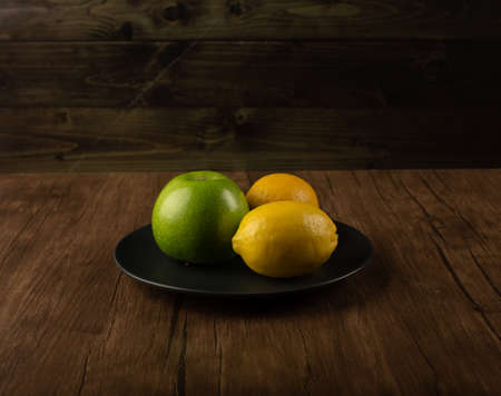 Apple and lemons on a wooden tableの写真素材