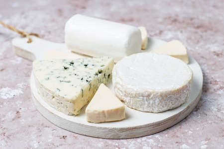 Various types of cheese on light brown background,top view