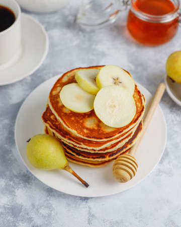 Homemade breakfast: american style pancakes served with pears and honey with a cup of tea on...