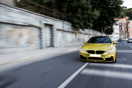Golden sport sedan car front view on the roadの写真素材