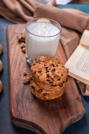 A glass of milk with sweet cookies on a wooden boardの写真素材