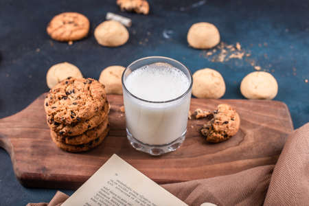 Variety of cookies with a glass of milk on a wooden board