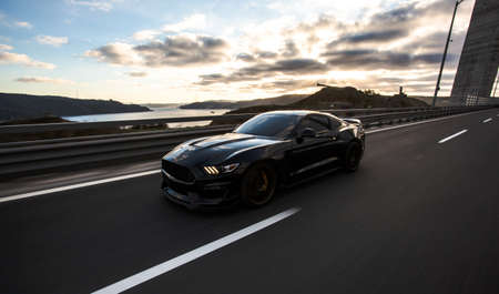 Black sport car driving on the road, front view