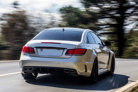 White sport sedan with red xenon lights on the test drive in the forestの写真素材