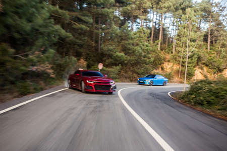 Red and blue luxury business class sedan racing on the highway