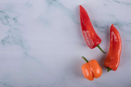 Three chili peppers on a blue marble tableの写真素材