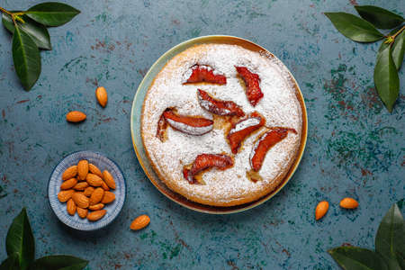 Homemade rustic plum cake with powdered sugar and almond,top viewの写真素材