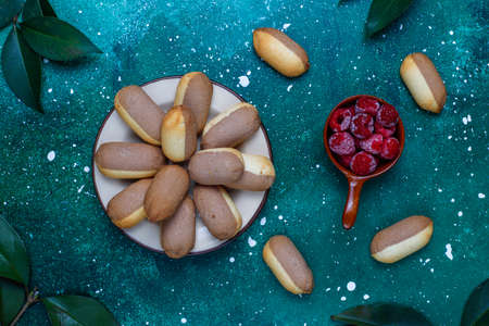 Cookies with raspberry jam filling and frozen raspberries on light background,top view