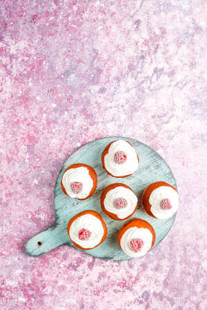 Cupcakes decorated whipped cream and frozen raspberries.