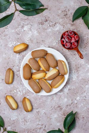 Cookies with raspberry jam filling and frozen raspberries on light background,top view