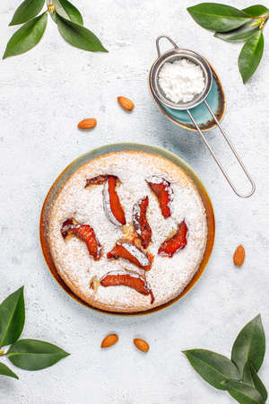 Homemade rustic plum cake with powdered sugar and almond,top viewの写真素材
