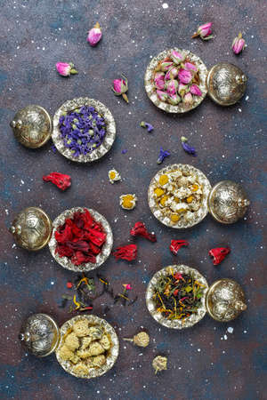 Assortment of dry tea in golden vintage mini plates.Tea types background:hibiscus,chamomile,mixed black tea,dry roses,butterfly pea teaの写真素材