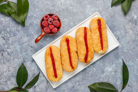 Puff pastry cookies with raspberry jam and frozen raspberries on light background