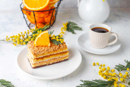 Orange cake decorated with fresh orange slices and mimosa flowers on light backgroundの写真素材