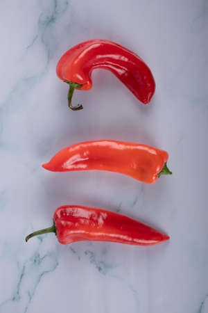 Three red chili peppers on a blue marbleの写真素材