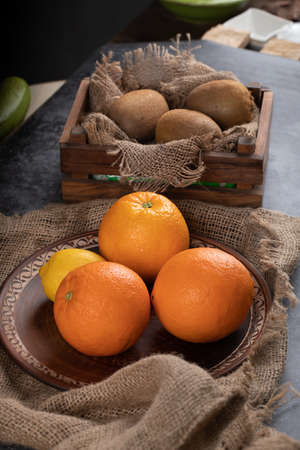 Orange and kiwies in a dark rustic background.の写真素材