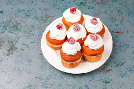 Cupcakes decorated whipped cream and frozen raspberries.の写真素材