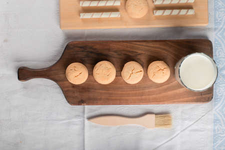 Butter cookies and a glass of milk on a wooden cutting board